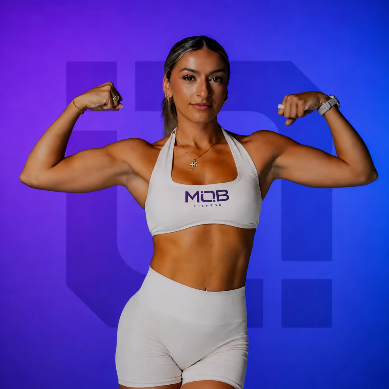 Coach Katelyn Rodriguez wearing MOB Fitness gear against a branded MOB backdrop